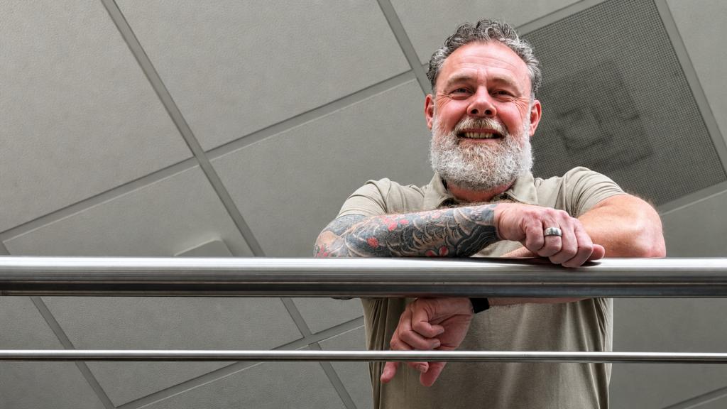 Marco kijkt lachend over de Railing
